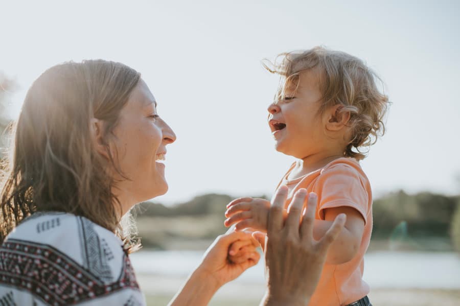 Mother and toddler laughing face to face